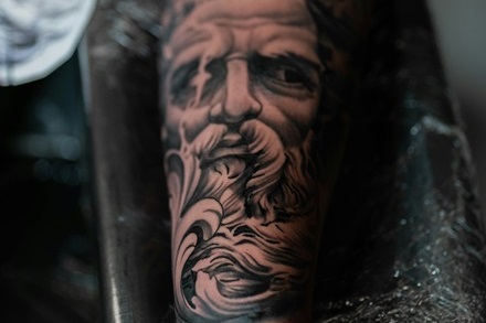 a forearm black and gray tattoo of zeus's head