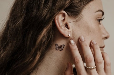 photo of a woman with a fine line butterfly tattoo behind her right ear