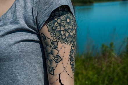 upper forearm black and gray tattoo of a few mandalas tied together with a fine line string