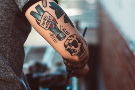 back upper forearm tattoo of the head of a hammer with words saying hard work